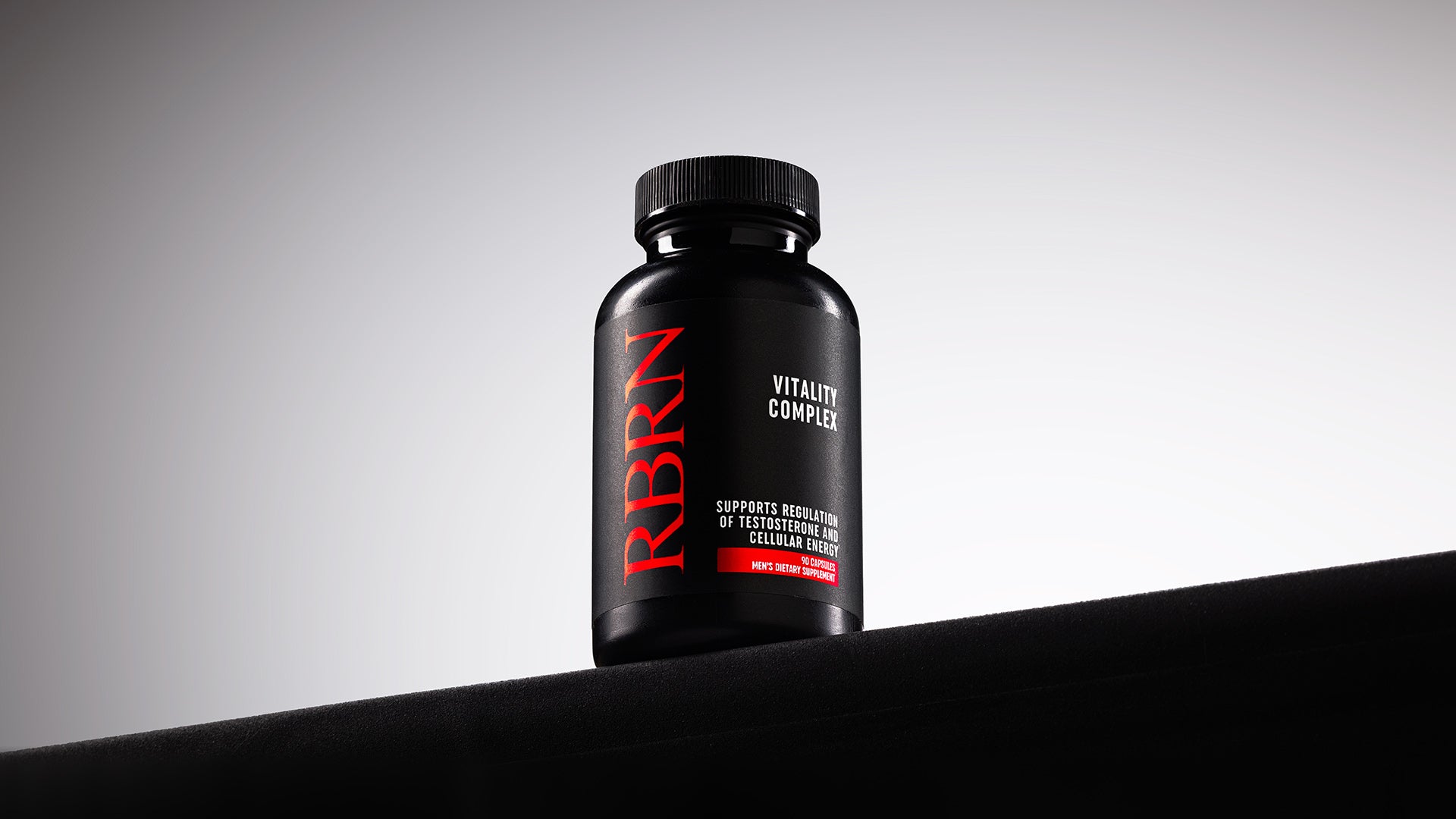 RBRN Vitality Complex bottle standing on a black ledge against a grey studio backdrop